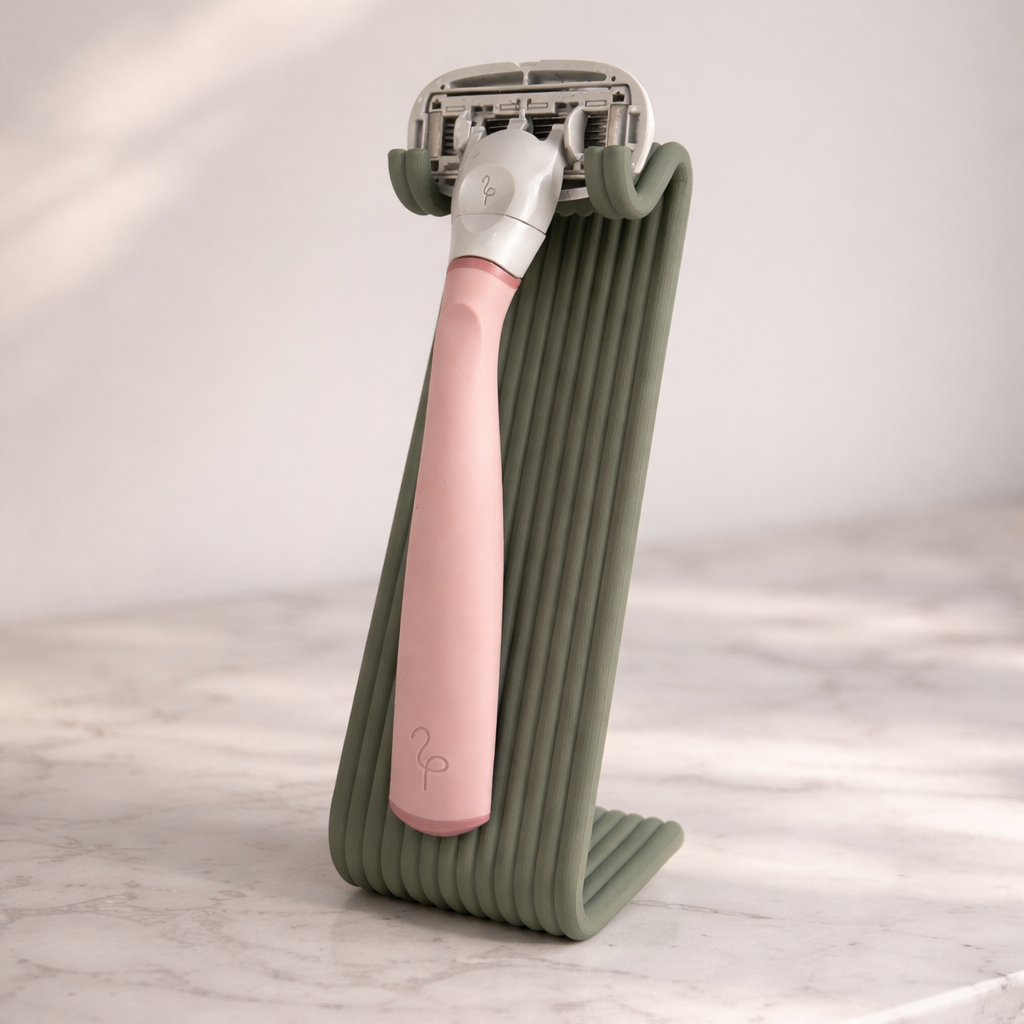 Pink razor with a green holder on a marble surface
